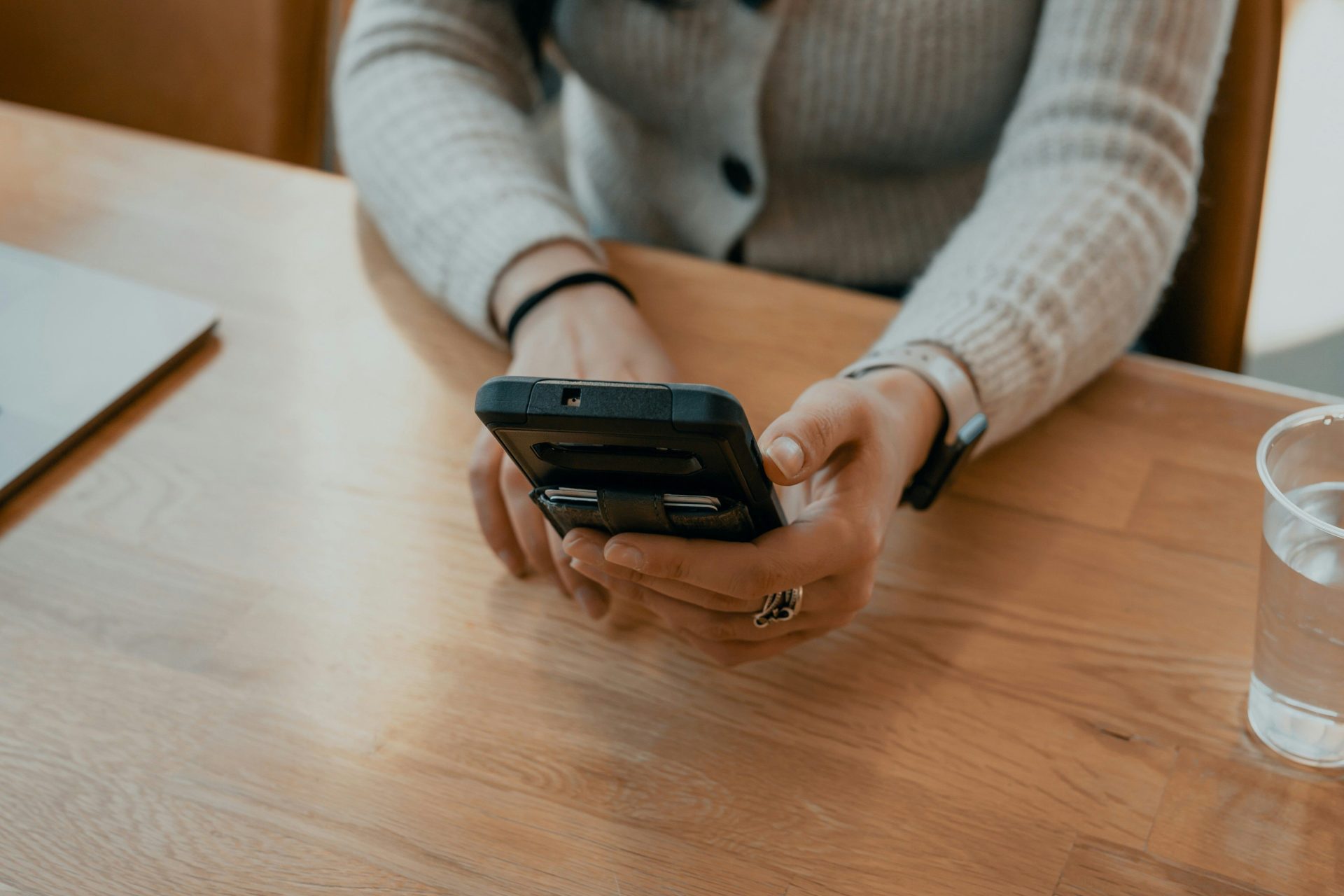 Frau im weißen Pullover hält ein schwarzes Smartphone